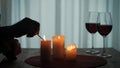 Romantic evening by candlelight. Hands of a man lighting candles with matches close up. Burning candles and glasses with Royalty Free Stock Photo