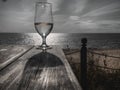 Romantic evening sunset with misty glass of white wine on background sea, on wooden table Royalty Free Stock Photo