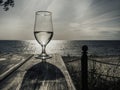 Romantic evening sunset with misty glass of white wine on background sea, on wooden table Royalty Free Stock Photo