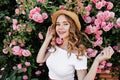 Romantic fair-haired girl posing with smile in front of beautiful flowers. Outdoor portrait of chee Royalty Free Stock Photo