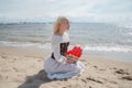 Romantic fashion beauty portrait of young lovely woman dreaming and sitting on sea beach outdoor Royalty Free Stock Photo