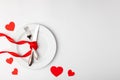 Romantic festive table setting on white background. Valentines day card template. Red ribbon, plate, silverware, vintage
