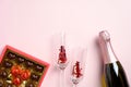 Romantic flat lay composition with champagne bottle, glasses, sweets on pink background. Happy Valentines Day celebration concept