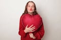Romantic flirting brown haired adult woman wearing red sweater holding heart shape balloon sending air kissing with pout lips