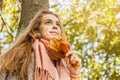 Romantic girl dreams in autumn fall park. Cute woman holding yellow maple leaf outdoors Royalty Free Stock Photo