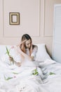 Romantic girl. Portrait of a girl in bed with natural flowers. Dreamy young woman with pink tulips resting in bedroom in morning Royalty Free Stock Photo