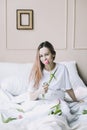 Romantic girl. Portrait of a girl in bed with natural flowers. Dreamy young woman with pink tulips resting in bedroom in morning Royalty Free Stock Photo