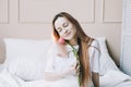 Romantic girl. Portrait of a girl in bed with natural flowers. Dreamy young woman with pink tulips resting in bedroom in morning Royalty Free Stock Photo