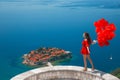 Romantic girl in red dress over Sveti Stefan island in Budva, Mo Royalty Free Stock Photo