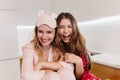 Romantic girls with shiny hair laughing while sitting in kitchen. Wonderful caucasian sisters in pyjamas posing with