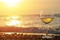 Romantic glass of wine sitting on the beach at colorful sunset Glasses of white wine against sunset, white wine on the sky backgro Royalty Free Stock Photo