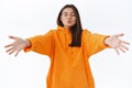 Romantic gorgeous girlfriend in orange hoodie, close eyes and fold lips for mwah, reaching hands forward to cuddle and