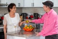 Romantic grandparents couple in a modern kitchen. Older man handing a fruit to his elderly wife while smiling. Royalty Free Stock Photo