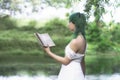 romantic green-haired girl reads a book in the midst of a surreal green landscape