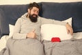 Romantic greeting. morning surprise from his valentine. happy valentines day. bearded man hold decoration heart in bed Royalty Free Stock Photo