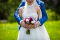 Romantic groom hugging beautiful bride with bouquet from behind