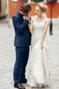 Romantic groom kissing hand of beautiful happy bride outdoors, newlywed couple portrait