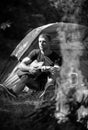 Romantic guy camping outdoors and sitting near tent. Handsome man playing guitar in forest with bonfire. Country music Royalty Free Stock Photo