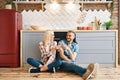 Romantic happy couple sitting on floor in kitchen and toasting champagne glasses Royalty Free Stock Photo