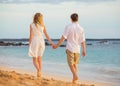 Romantic happy couple walking on beach at sunset