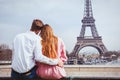 Romantic holidays in France, couple sitting together near Eiffel tower in Paris