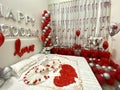 Romantic honeymoon bedroom decoration with a couple of swans kissing made from towels, balloons, and rose petals Royalty Free Stock Photo