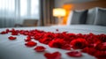 Romantic hotel room with red rose petals on bed for intimate evening Royalty Free Stock Photo