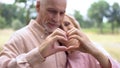 Romantic husband and wife showing heart gesture by hands, old age tenderness Royalty Free Stock Photo