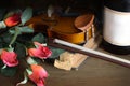 Romantic image of a violin with a glass of red wine and red roses on a rustic wooden table. Royalty Free Stock Photo