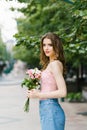 Romantic image of a young girl walking on a summer street in the Park with a bouquet of roses
