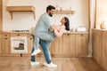 Romantic indian couple having fun together, feeling happy, dancing in kitchen interior, full length, side view Royalty Free Stock Photo