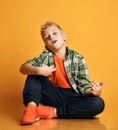 Romantic kid boy teenager in casual clothing and sneakers sits on floor playing an imaginary guitar and sings Royalty Free Stock Photo