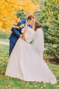 Romantic kiss of newly married couple under tree with yellow leaves in autumn park Royalty Free Stock Photo