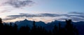 romantic large panorama with alpine mountains and trees silhouettes on sunset