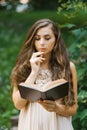 Romantic long haired young beautiful woman holding a book and reading it