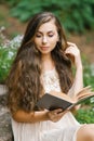 Romantic long haired young beautiful woman reading a book