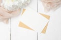 Romantic love letter concept. Flat lay kraft paper envelope, blank note, peony flowers and beige cloth on white wooden table. Top Royalty Free Stock Photo