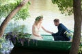 Romantic love story in boat. Woman with wreath and white dress. European tradition Royalty Free Stock Photo