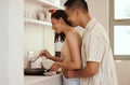 Romantic, loving and caring couple cooking and bonding while hugging in the morning at home. Smiling husband and wife