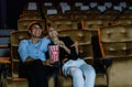 Romantic loving couple at the cinema. Portrait of handsome man hugging her girlfriend and eating popcorn while watching a film at Royalty Free Stock Photo