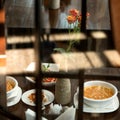 Romantic lunch. Delicious dishes and rose flower in vase at restaurant table. Food concept. Square format. Side view Royalty Free Stock Photo