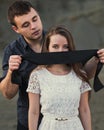 Romantic man blindfolding his woman with black ribbon. Love blind concept Royalty Free Stock Photo