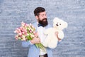 Romantic man with flowers and teddy bear. Romantic gift. Macho getting ready romantic date. Man wear blue tuxedo bow tie Royalty Free Stock Photo