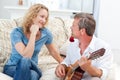 Romantic man playing guitar for her wife at home