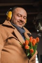 A romantic man smiles and looks at the camera with a bouquet of tulip flowers. Vertical photo Royalty Free Stock Photo