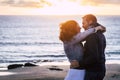 Romantic mature couple in love kissing outdoor against an amazing sunset at the beach with ocean background. Relationship with man Royalty Free Stock Photo