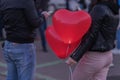 Romantic meeting of guy and girl. Two LED balloons in form of scarlet burning hearts in evening in girl`s hand.Romantic