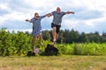 Romantic middle-aged couple holding hands jumping from a stone, the concept of a happy relationship