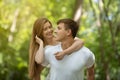 Romantic millennial couple looking at each other lovingly at summer park