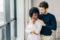 Romantic mixed race couple standing by the window thinking about their future. Royalty Free Stock Photo